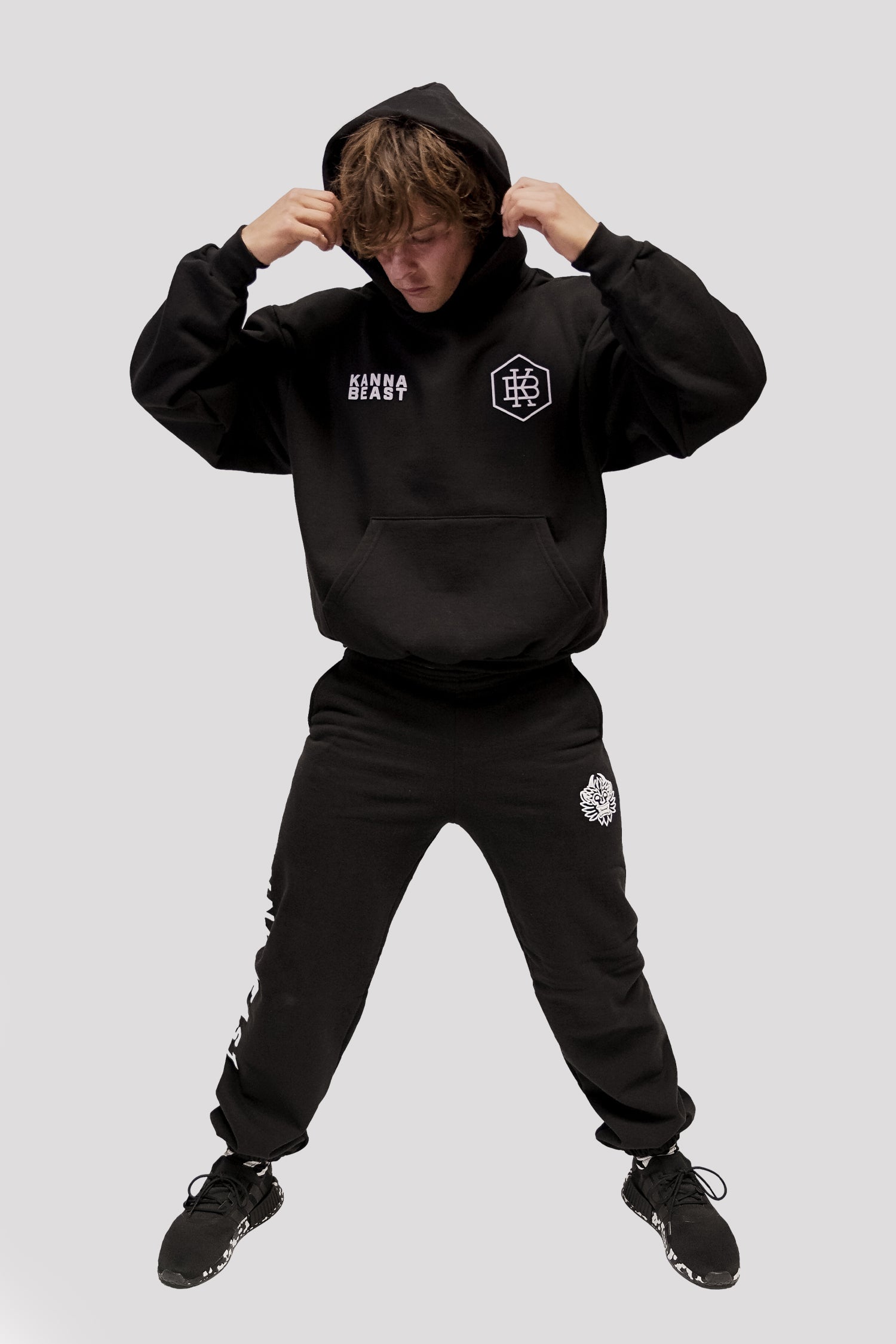 Male model with hands above head wearing Kanna Beast Hoodie and Sweatpants.