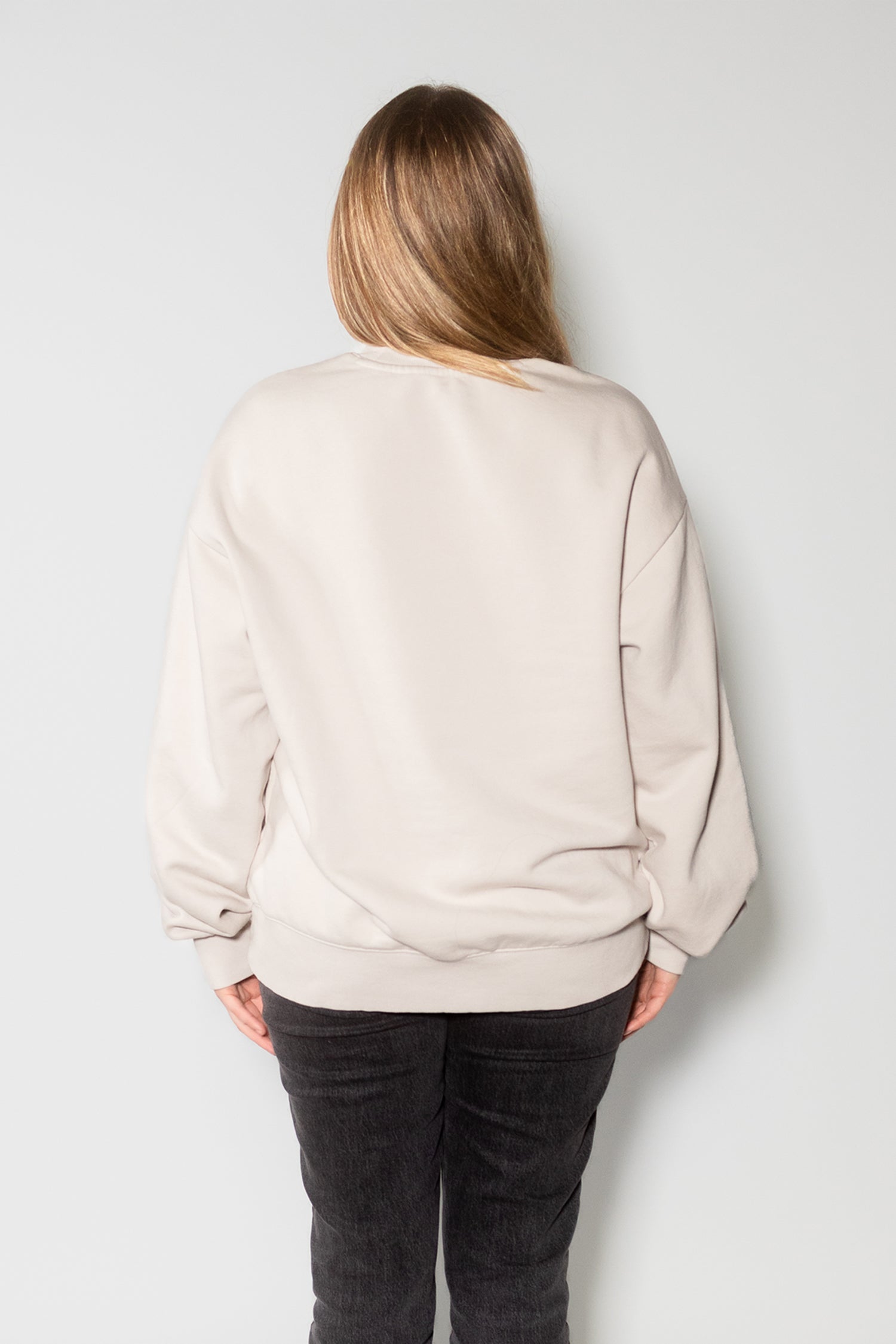 Female model wearing bone crewneck and facing backwards.