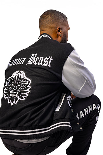 Male model wearing Kanna Beast Letterman Jacket in black and white, showing the back of the jacket with Kanna Beast written and a chenille patch of our logo. 