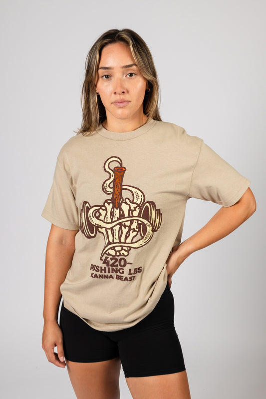 Female model wearing beige Kanna Beast graphic t-shirt featuring a dumbbell and smoke design with the phrase ‘420 Pushing LBS.